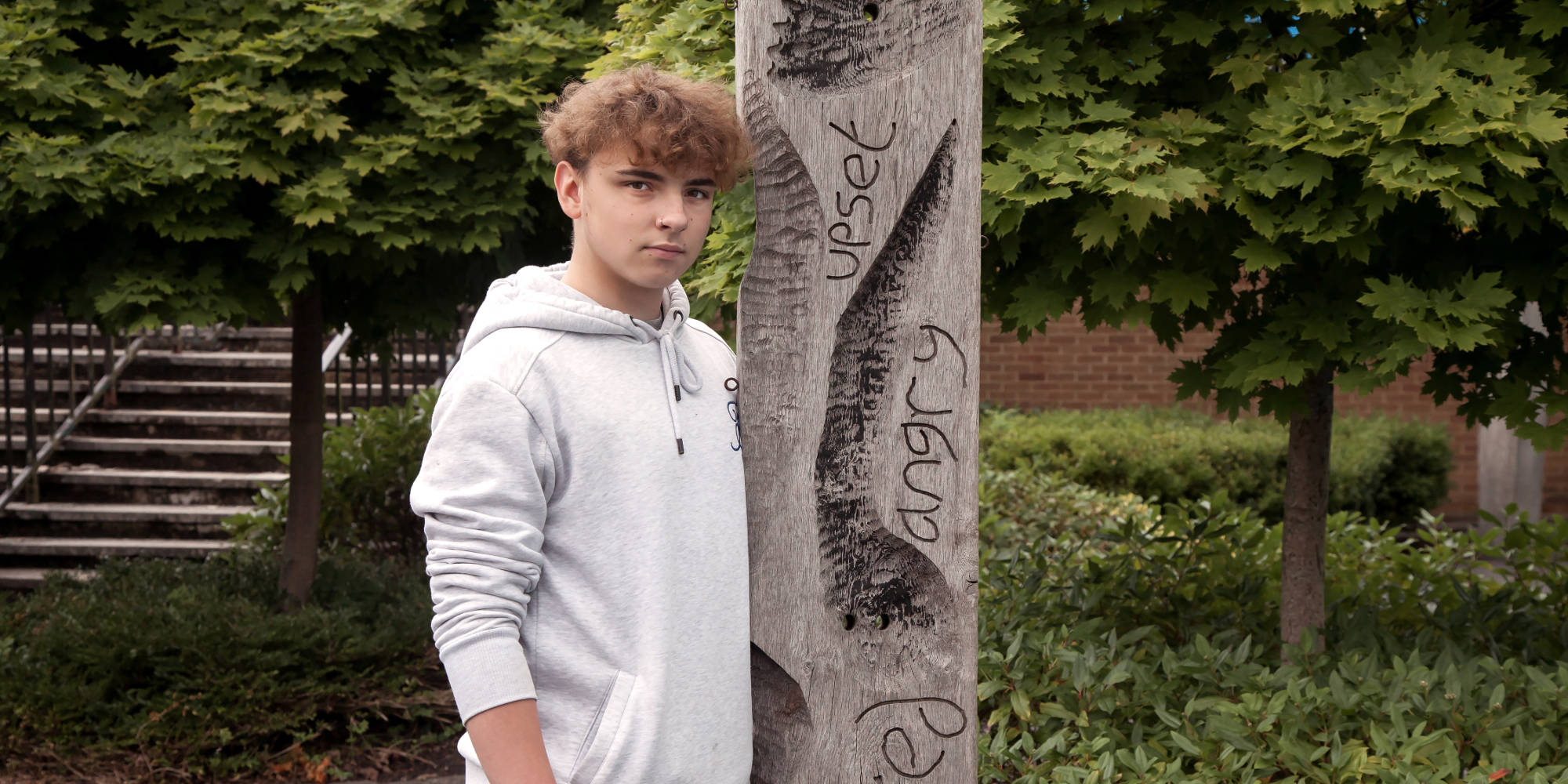 Boy next to tree with Angry written on it