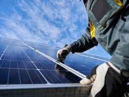 A worker fixing a solar panel on a roof