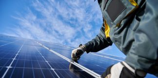 A worker fixing a solar panel on a roof