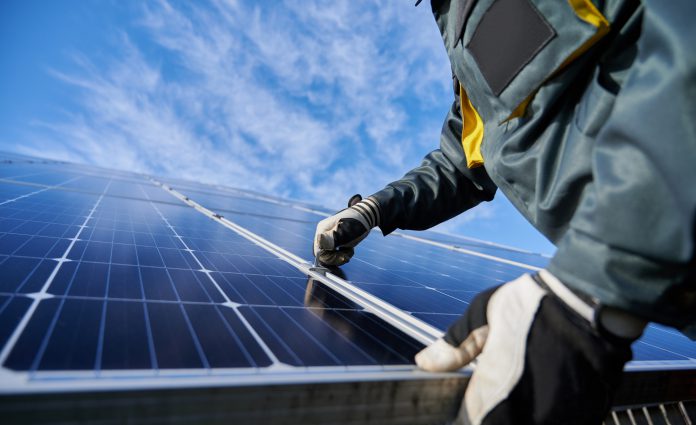 A worker fixing a solar panel on a roof