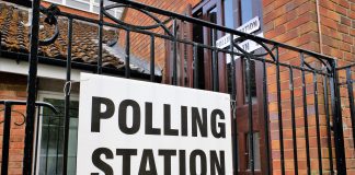 A sign saying polling station on a fence outside a building