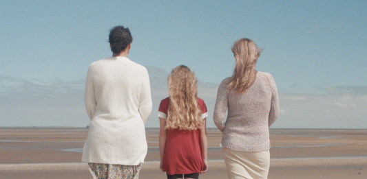 A picture of three people stood on a beach taken from the fostering recruitment film 'Any of Us'.