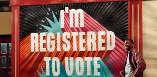 man standing near shop front with wording 'I'm registered to vote'