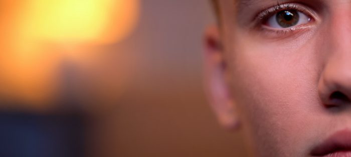 Handsome teenage boy looking directly to camera, background, half-face close-up