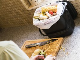 Food waste on a chopping board being placed in to a kitchen caddy