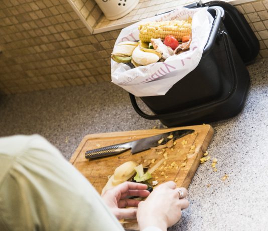 Food waste on a chopping board being placed in to a kitchen caddy