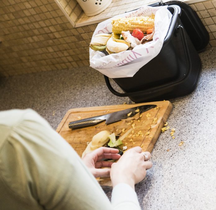Food waste on a chopping board being placed in to a kitchen caddy