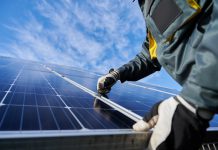 A worker fixing a solar panel on a roof