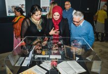 Attendees of the launch event discuss one of the pieces on display at the exhibition