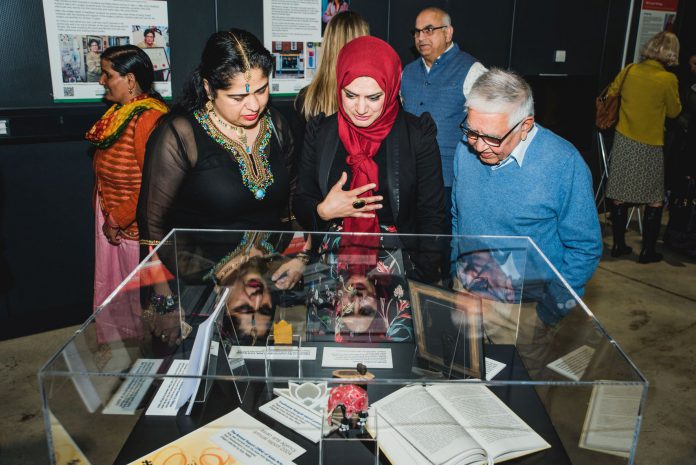 Attendees of the launch event discuss one of the pieces on display at the exhibition