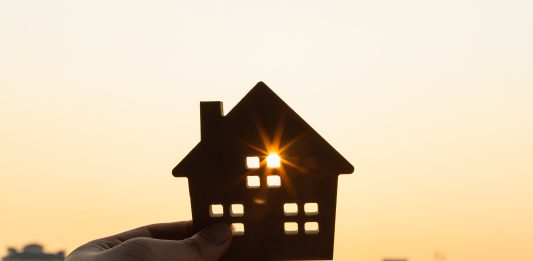An image of a model of a house held up against the sun