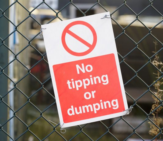 Sign on fence saying No tipping or dumping