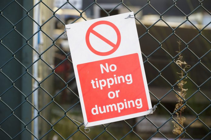 Sign on fence saying No tipping or dumping