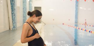 Pregnant woman relaxing near a swimming pool in a swimsuit