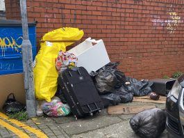 A photograph of fly-tipped waste near a lamp post