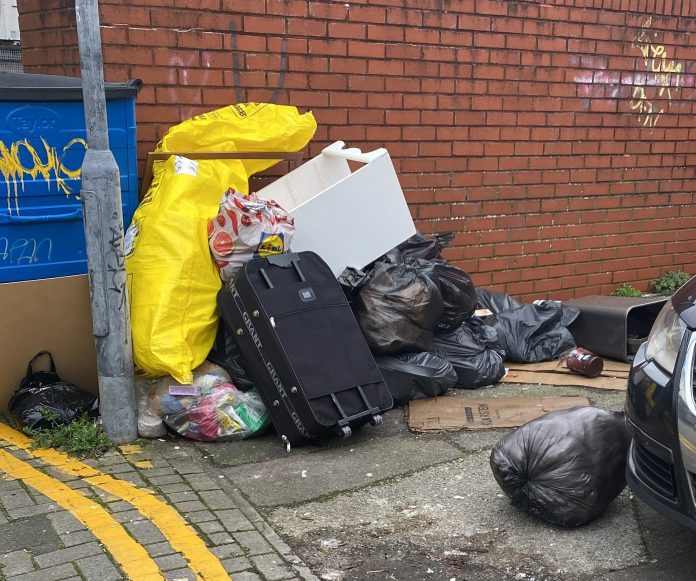 A photograph of fly-tipped waste near a lamp post