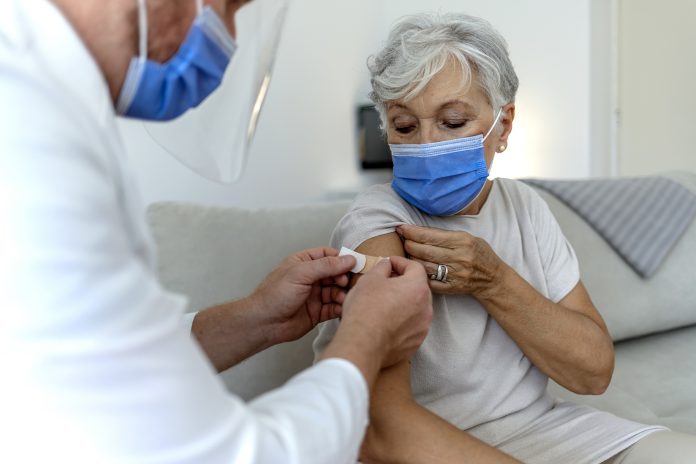 A male doctor puts a band aid on a woman's arm following a vaccine injection