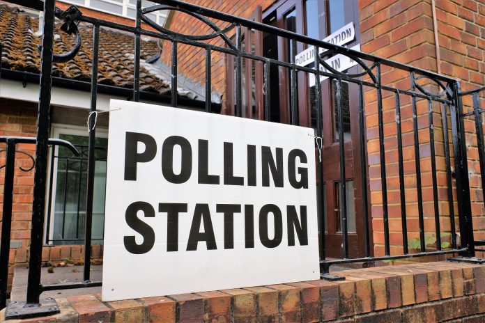 A sign saying polling station on a fence outside a building