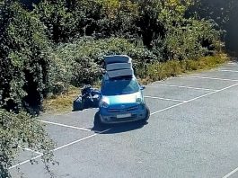 A photo of a car next to several black bin bags in a car park area