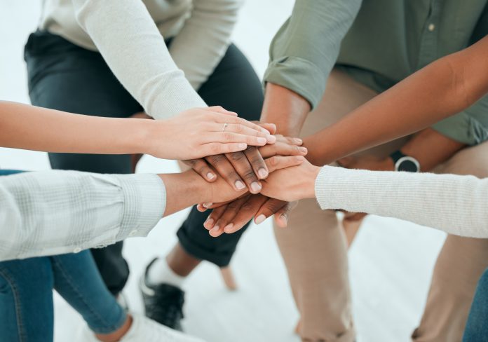 A group of people sitting together and stacking their hands in the middle