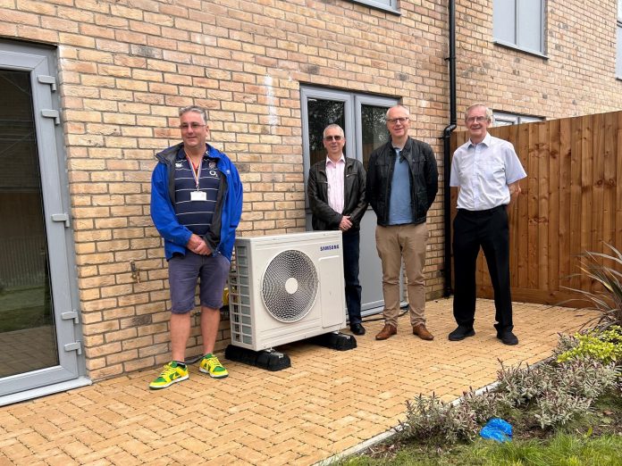 Cllr Monk (left) with colleagues inspecting an air source heat pump installed at the new homes.