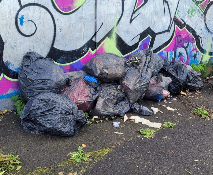Black bin-liners full of waste dumped on a pavement