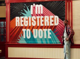 man standing near shop front with wording 'I'm registered to vote'