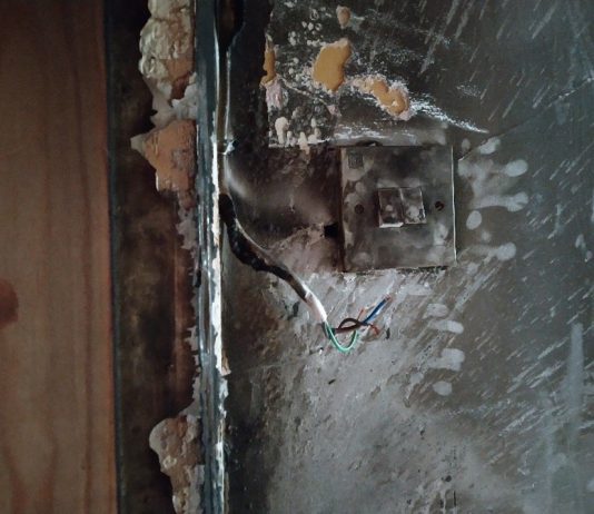 A photo of a fire damaged area with hazardous electrics is attached.