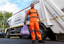 New hygiene and nappy waste collection service to be introduced – express an interest Photo of man standing on a road in orange high vs overalls holding a full waste sack with a waste lorry in the background.