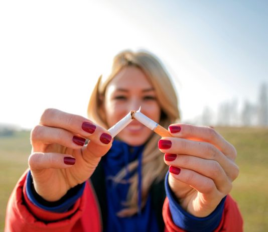 A young woman snapping a cigarette in half