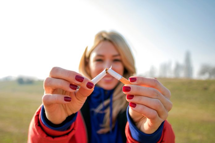A young woman snapping a cigarette in half