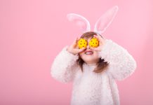 Young girl with Easter eggs held over her eyes