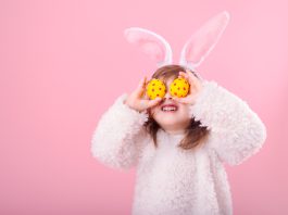 Young girl with Easter eggs held over her eyes