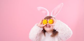 Young girl with Easter eggs held over her eyes