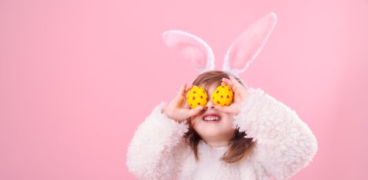 Young girl with Easter eggs held over her eyes
