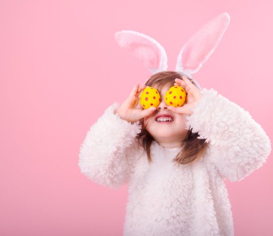 Young girl with Easter eggs held over her eyes