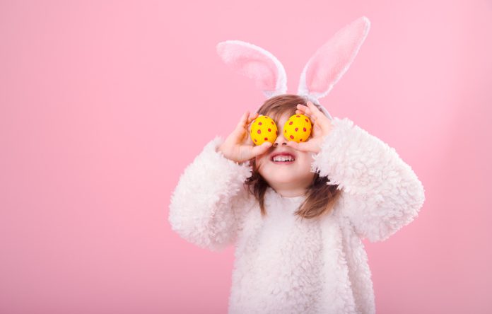 Portrait of a little girl with Bunny ears and Easter eggs Young girl with Easter eggs held over her eyes