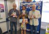 Chair of South Gloucestershire Council, councillor Adrian Rush (right) is joined by a family (centre) and member of staff (left), at Emersons Green Library to mark the launch of the Summer Reading Challenge 2026.
